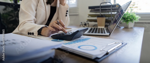 Quadro em tela Businesswoman accountant using calculator and laptop for matching financial data