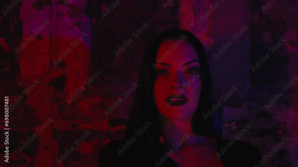  A beautiful goth women looking at Christmas sparkles in her hand, dark makeup and a Halloween costume. blue and red light on the background. The enchanting scene unfolds indoors during nighttime.