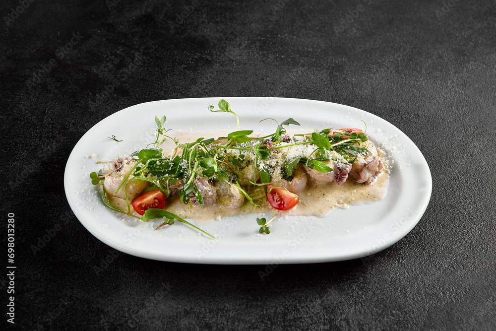 Creamy seafood assortment garnished with fresh greens and cherry tomatoes on a white oval plate Creamy seafood assortment garnished with fresh greens and cherry tomatoes on a white oval plate