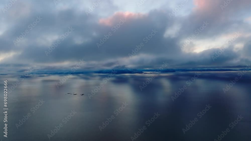 aerial cinematic view over the norwegian sea under the rose clouds with mountains covered with snow on background aerial cinematic view over the norwegian sea under the rose clouds with mountains covered with snow on background