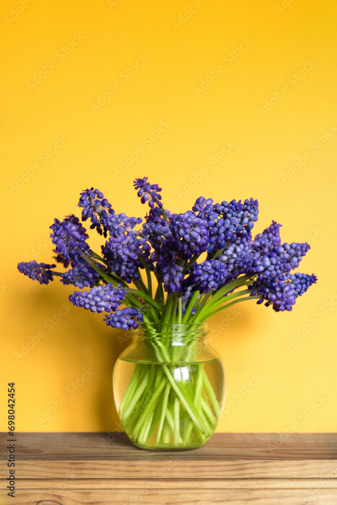 Minimal floral arrangement of a bouquet of blue flowers in a transparent vase on yellow. Happy mother's day, birthday, wedding composition. Blank greeting card, invitation and mockup. Minimal floral arrangement of a bouquet of blue flowers in a transparent vase on yellow. Happy mother's day, birthday, wedding composition. Blank greeting card, invitation and mockup.