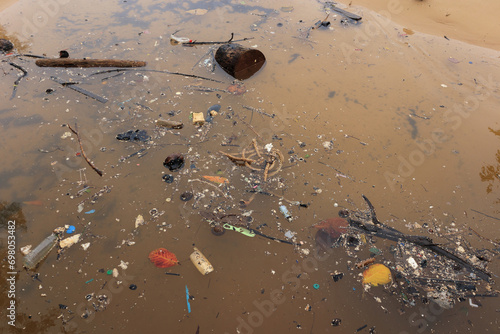 garbage floating in sea water by beach, dirty sea pollution, waste on beach after low tide, environmental pollution