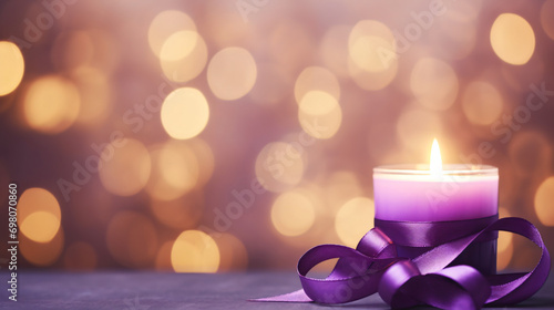 A candle with purple ribbon on blurred purple background
