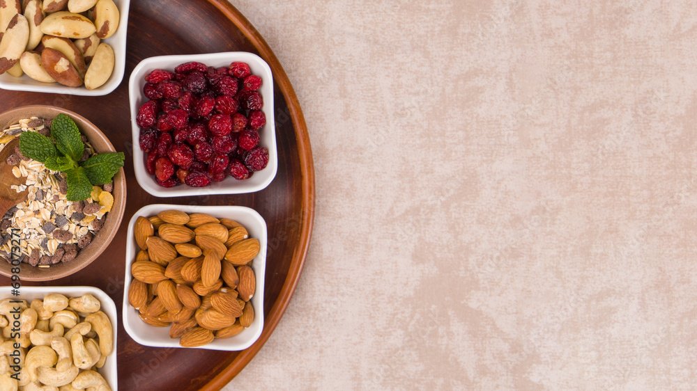 Different types of nuts, dried cranberries and muesli in plates. Copy space.