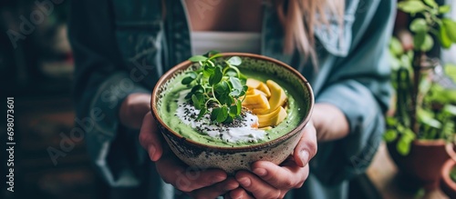 Female holding vegan avocado smoothie bowl for breakfast. photo