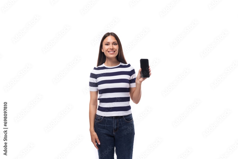 energetic young caucasian brunette woman in a striped black and white t-shirt shows the screen of a mobile phone with a mockup energetic young caucasian brunette woman in a striped black and white t-shirt shows the screen of a mobile phone with a mockup