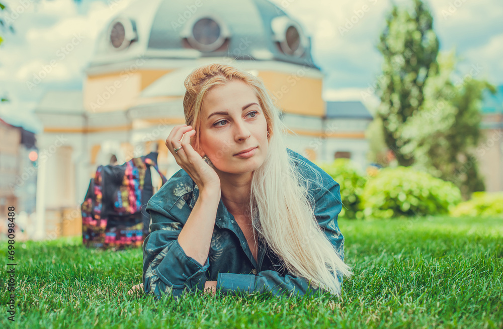 Young European Blonde student girl resting after hard day on a grass at city park. Youth psychology concept Young European Blonde student girl resting after hard day on a grass at city park. Youth psychology concept