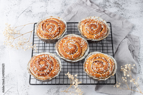 Freshly baked cinnamon buns rolls on retro metal baking rack with grey linen napkin. Traditional swedish sweet pastry kanelbulle. photo