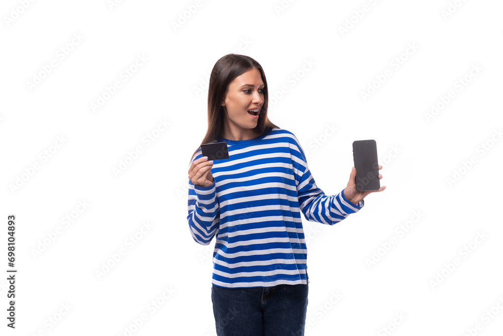 young joyful caucasian woman with dark hair dressed in a blue striped sweatshirt watches video on the phone on a white background young joyful caucasian woman with dark hair dressed in a blue striped sweatshirt watches video on the phone on a white background