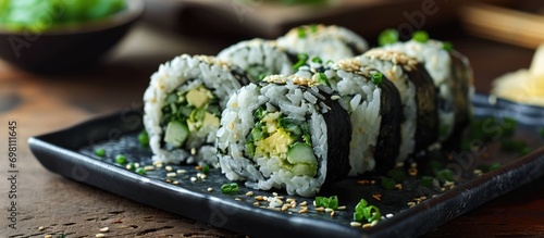 Rice and avocado maki sushi roll served on a black plate in traditional Japanese cuisine.