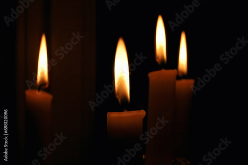 Obraz na plátne Lighting the Darkness: Four Candles Illuminating a Dark Room