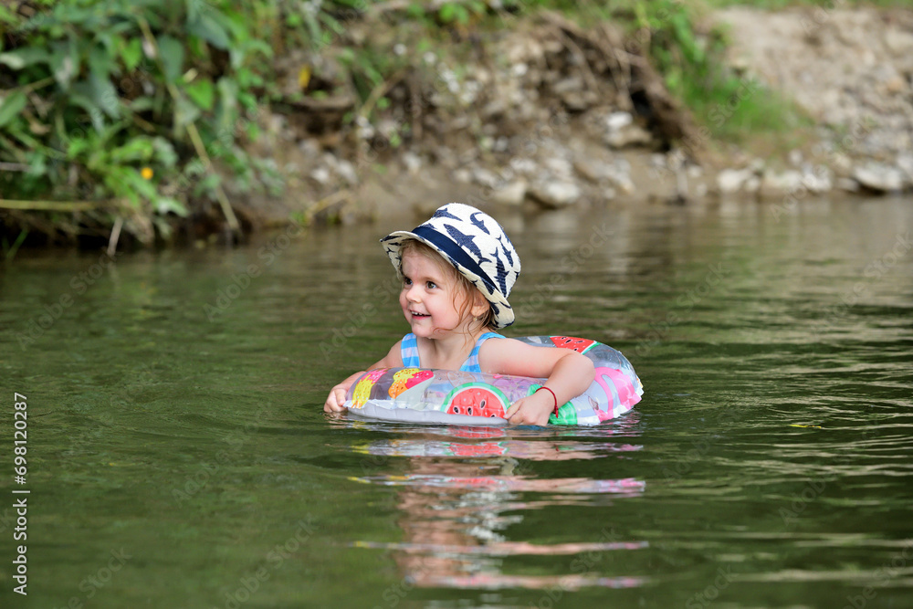 A little girl learns to swim in a river using a lifebuoy