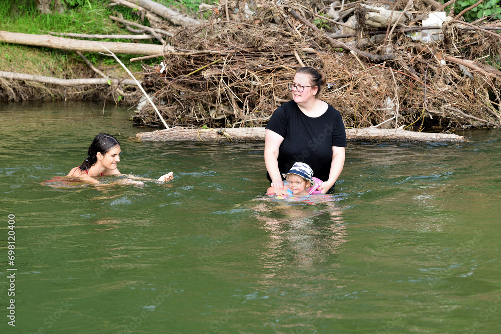 A little girl learns to swim in a river using a lifebuoy