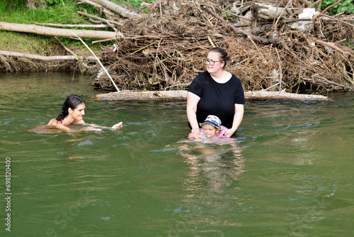 Obraz na płótnie A little girl learns to swim in a river using a lifebuoy w salonie