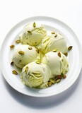 Plate of pistachio ice cream scoops on white background, top view.