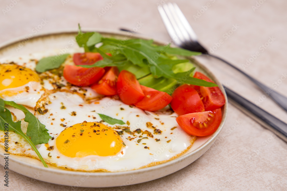 Fried eggs with tomatoes and arugula on a plate. Fried eggs with tomatoes and arugula on a plate.