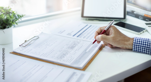 A man work on desk reading document before filling out various information in the application to start a new job, Close-up at hand holding pen