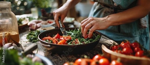 Close-up image of woman's hands preparing salad with organic vegetables on a table.