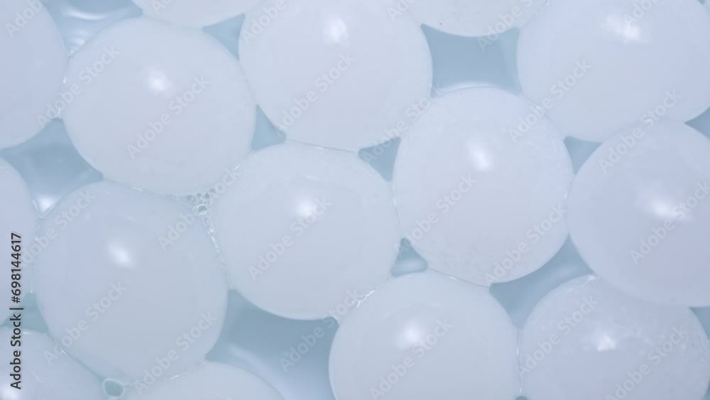 Close up shot of fluid substance on the white background. Cosmetic product gel or serum in white balls rotating on Petri dish, abstract background. Close up shot of fluid substance on the white background. Cosmetic product gel or serum in white balls rotating on Petri dish, abstract background.