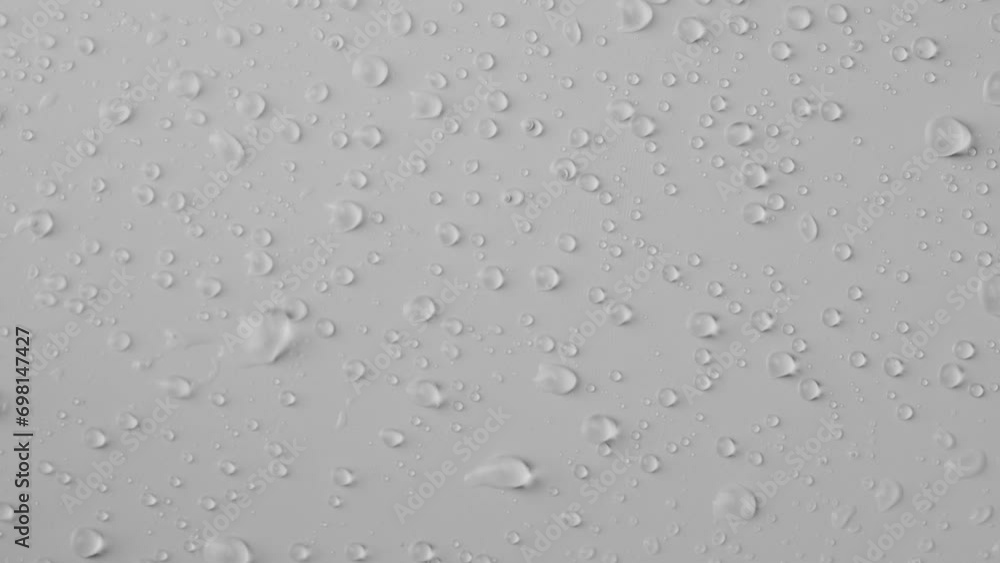 Close up shot of transparent glass on the white background. Many water drops on the surface being blown away by the air flow creating abstract pattern. Close up shot of transparent glass on the white background. Many water drops on the surface being blown away by the air flow creating abstract pattern.