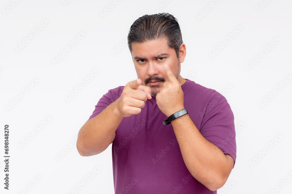 A distrustful middle aged man warning someone he is keeping an eye on him. Viewing someone with suspicion. Wearing a purple waffle shirt, Isolated on a white background. A distrustful middle aged man warning someone he is keeping an eye on him. Viewing someone with suspicion. Wearing a purple waffle shirt, Isolated on a white background.