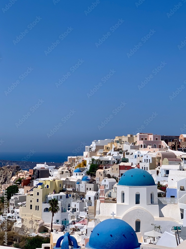 Beautiful Oia town on Santorini island, Greece. Traditional white architecture and greek orthodox churches with blue domes over the Caldera, Aegean sea in the beautiful town of Oia.	