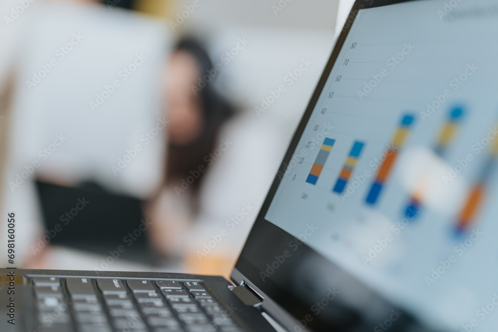 A businesswoman analyzing statistics and doing paperwork in a cozy workplace, planning and strategizing for successful business growth. Focus on lap top with graph charts on the screen. A businesswoman analyzing statistics and doing paperwork in a cozy workplace, planning and strategizing for successful business growth. Focus on lap top with graph charts on the screen.