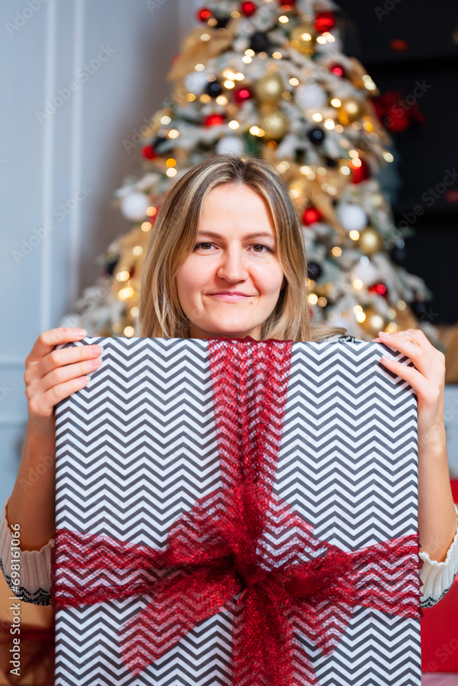 a girl with New Year's gifts on the background of a Christmas tree. New Year's photo shoot of a girl in a photo studio. blonde woman in a Christmas sweater a girl with New Year's gifts on the background of a Christmas tree. New Year's photo shoot of a girl in a photo studio. blonde woman in a Christmas sweater