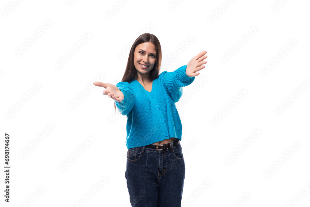 young positive pretty caucasian woman with black hair is dressed in a stylish blue cardigan and jeans on a white background young positive pretty caucasian woman with black hair is dressed in a stylish blue cardigan and jeans on a white background