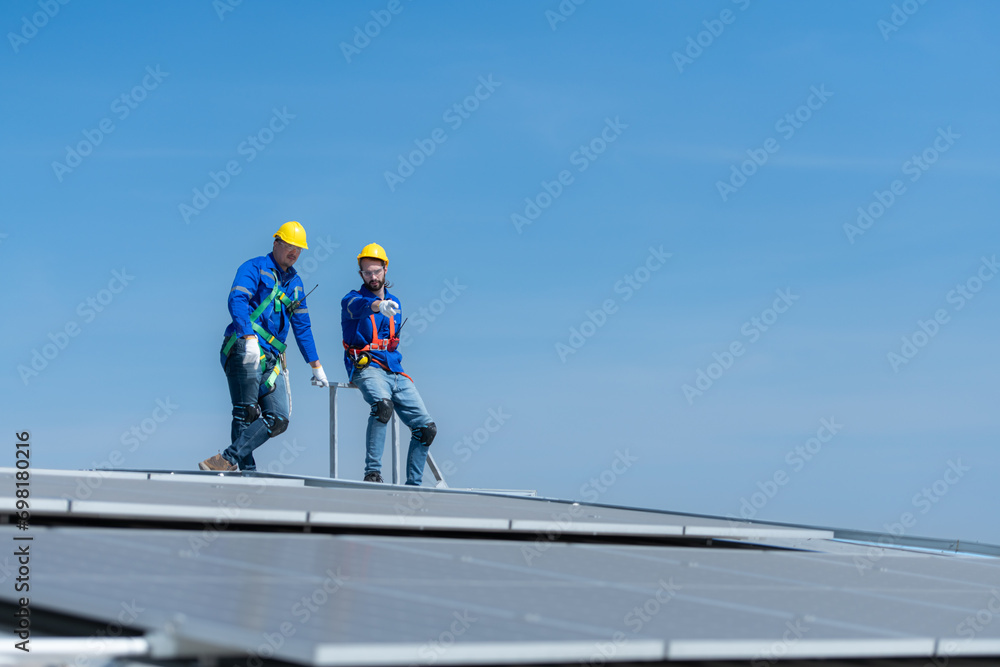 A young technician intern working on solar panels is fear of heights with senior engineers who are always helping out A young technician intern working on solar panels is fear of heights with senior engineers who are always helping out