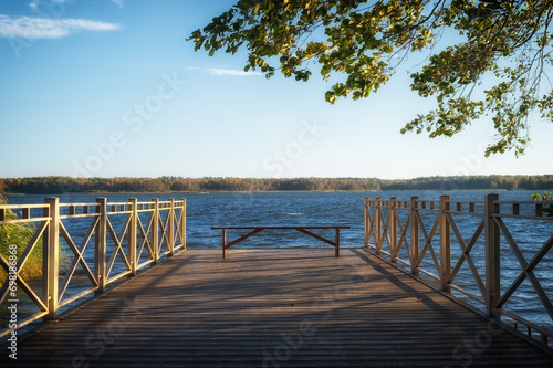 Empty wooden bench in front of the lake in the park on the pier. Background