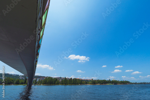 A view of the Mondego River in Coimbra, Portugal, under a clear sky, with trees and a pedestrian bridge. Landscape background and wallpaper.