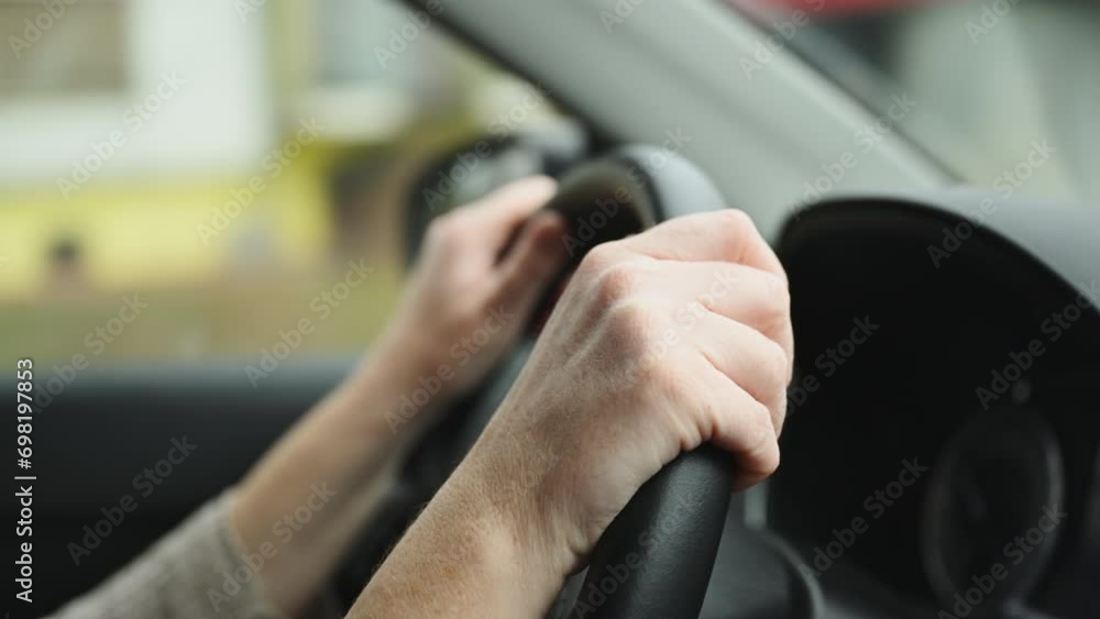Female driver is driving car along the country road, closeup of hands on vehicle steering wheel, 4K footage