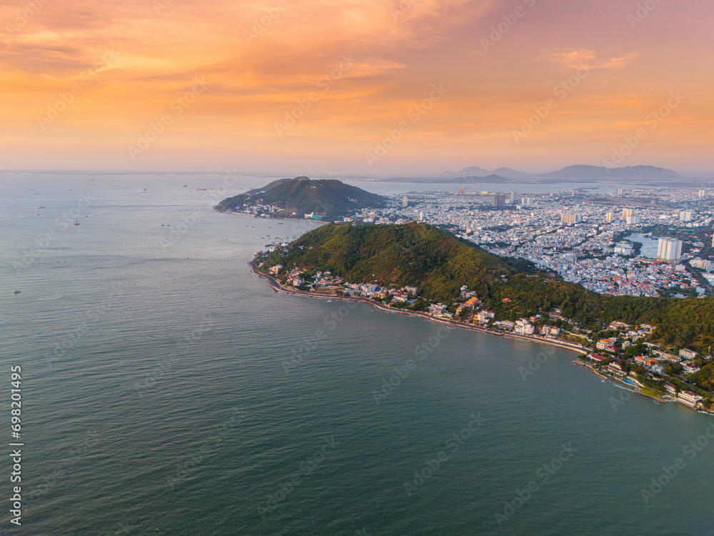 Panoramic coastal Vung Tau view from above, with waves, coastline, streets, coconut trees, Mount Nho in Vietnam behind the statue of Christ the King