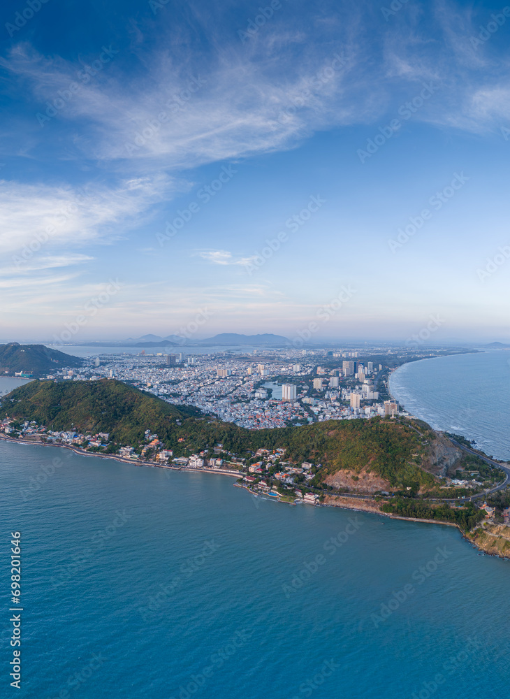 Panoramic coastal Vung Tau view from above, with waves, coastline, streets, coconut trees, Mount Nho in Vietnam behind the statue of Christ the King