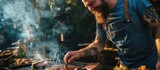 Cooking, a bearded man in a jeans apron and tattooed hand, smiling while grilling meat with oil, creating a flavorful steak.