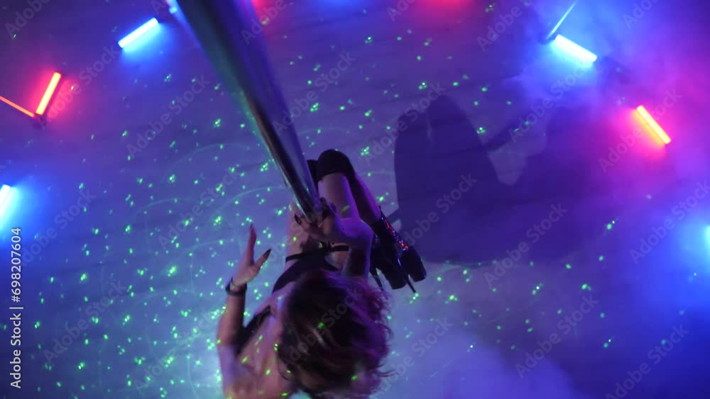 Sexy woman dances a pole dance in a disco club. Erotic dance on a pole