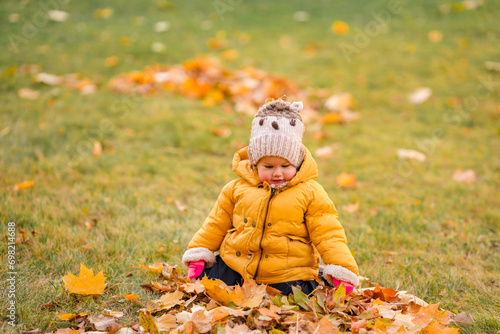 Cute baby toddler child in yellow jacket in autumn park in leaves