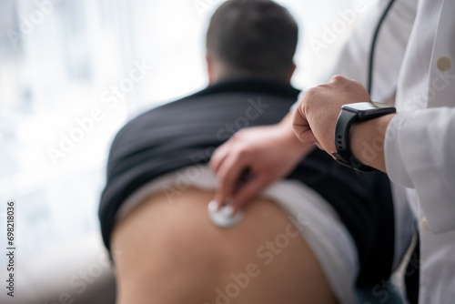 Doctor examining his patient checks his smart watch