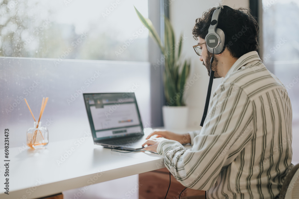Business person sitting on working desk next to the window working on lap top. Copy space. Business person sitting on working desk next to the window working on lap top. Copy space.