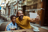 Stepfather taking selfie with child son at city cafe