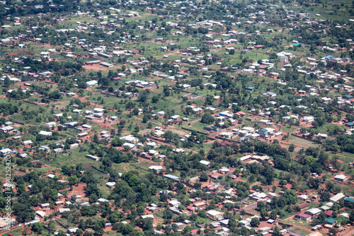 View from helicopter overflies African villages made of mud in traditional style (tukul houses) surrounded by tick green jungle