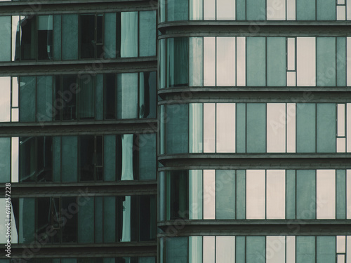 Glass building from front angle near sea. Glass reflecting water and sun. Abstract and modern fragment of the facade.