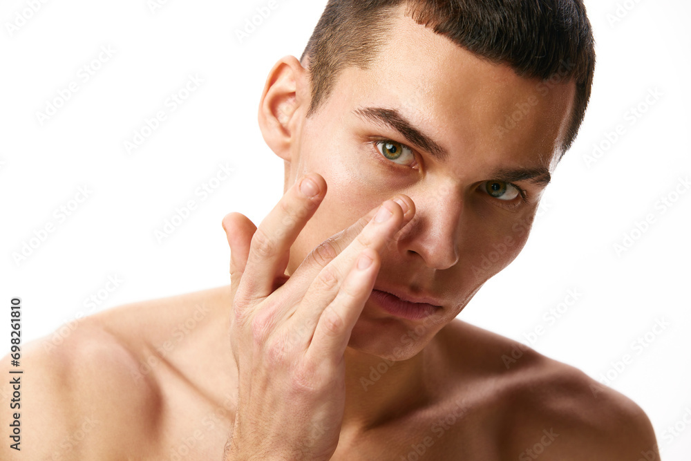 Portrait of handsome young man with brown short hair and spotless, clear face, taking care after skin against white studio background. Concept of male beauty, skin care, spa, cosmetology, men's health Portrait of handsome young man with brown short hair and spotless, clear face, taking care after skin against white studio background. Concept of male beauty, skin care, spa, cosmetology, men's health