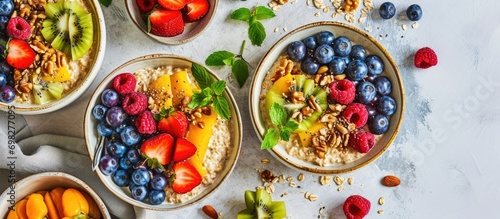 Healthy breakfast or snack with spelt porridge, fruits, berries, and nut topping on a bright background.