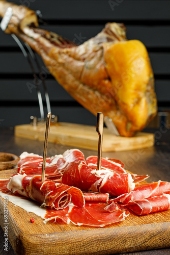 Slices of jamon serrano, jamon iberico, smoked sausage, ham or prosciutto crudo parma on wooden board with. Wooden background. Still life. Selected focus.