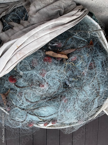 Used Fishing net with buoys, plastic floats  and ropes stored in a bag near boat. Fishing industry waste