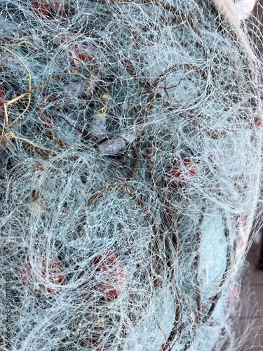 Used Fishing net with buoys, plastic floats  and ropes stored in a bag near boat. Fishing industry waste