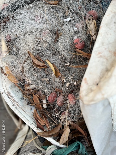 Used Fishing net with buoys, plastic floats  and ropes stored in a bag near boat. Fishing industry waste
