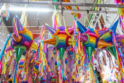 Colorful piñatas of different shapes and sizes hanging over the stalls of a traditional Mexican market.